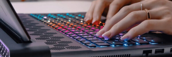 The Best Laptops Hands typing on a laptop keyboard with LED backlighting.