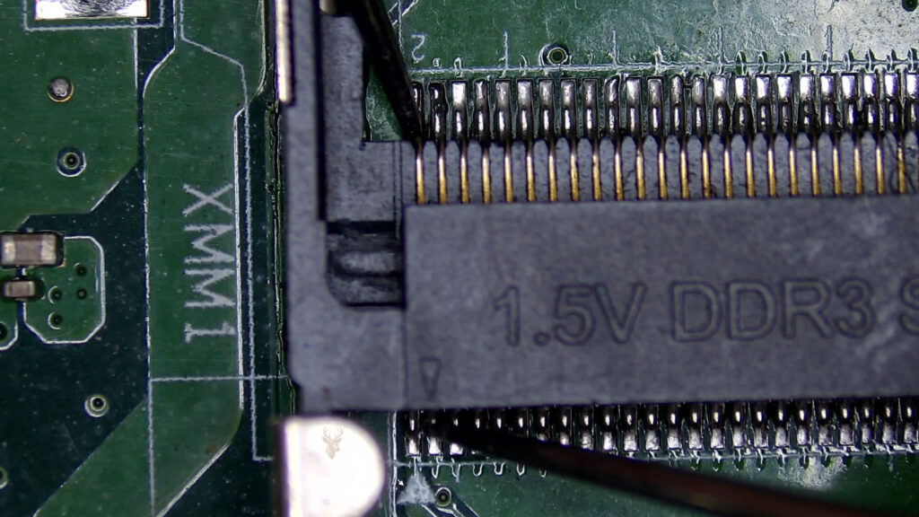 Multimeter measuring 1.5V at a laptop memory slot.