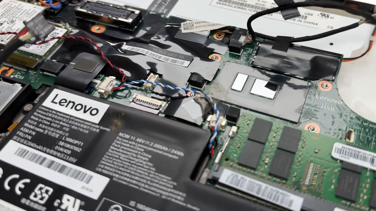 Opened Lenovo laptop showing multiple internal cables, ribbon connectors, and component access points during careful repair inspection.