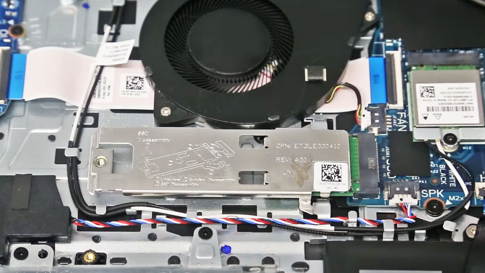 Dell laptop opened for internal inspection showing the motherboard, cooling fan, M.2 SSD, and Wi-Fi card cables