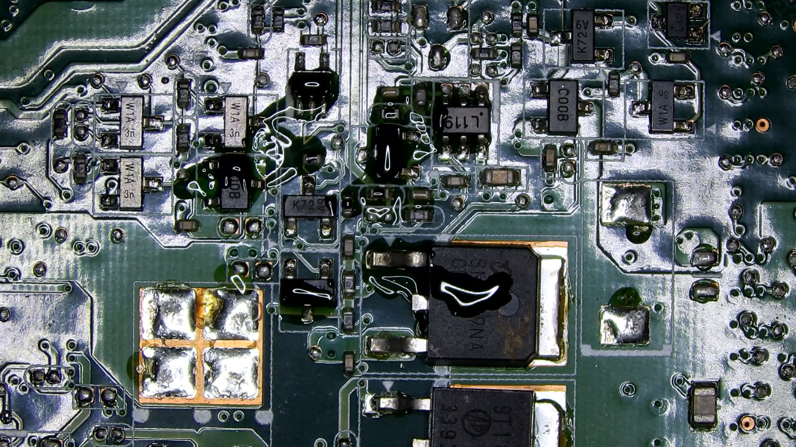 Laptop motherboard with visible liquid damage around transistor components