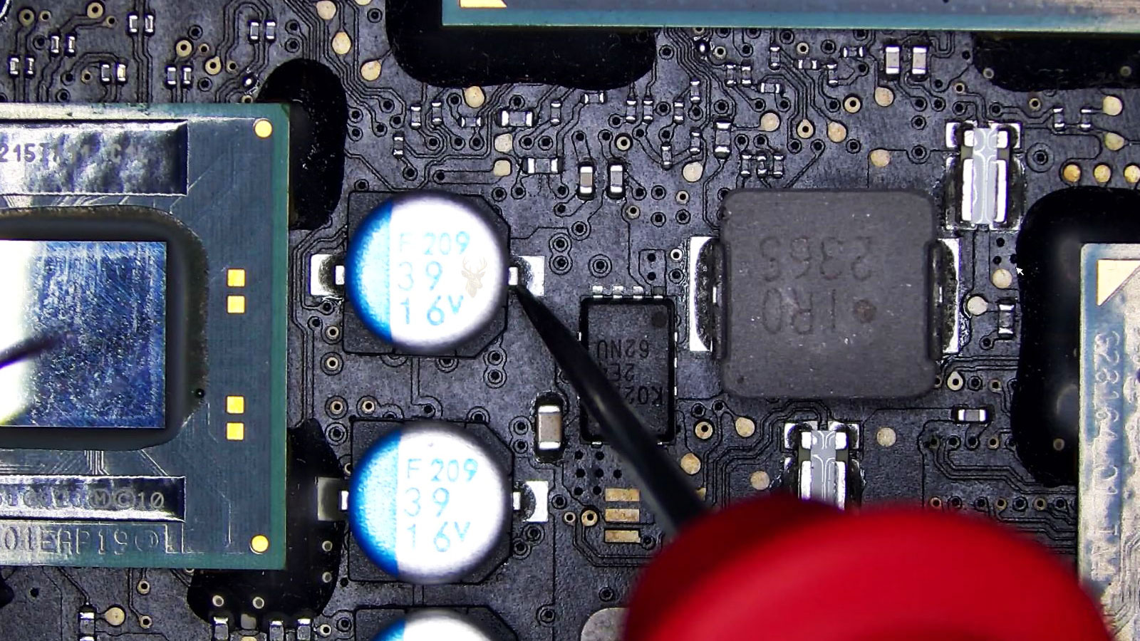 Multimeter probe measuring the positive side of a 39uF 16V capacitor on a computer circuit board.