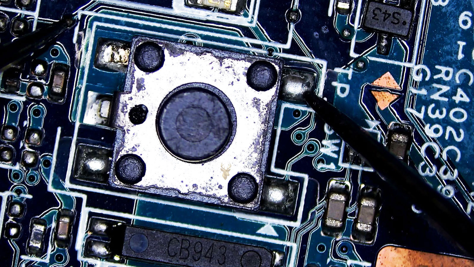 Close-up of a computer circuit board button being measured with a multimeter from one button leg to a solder joint on the board.
