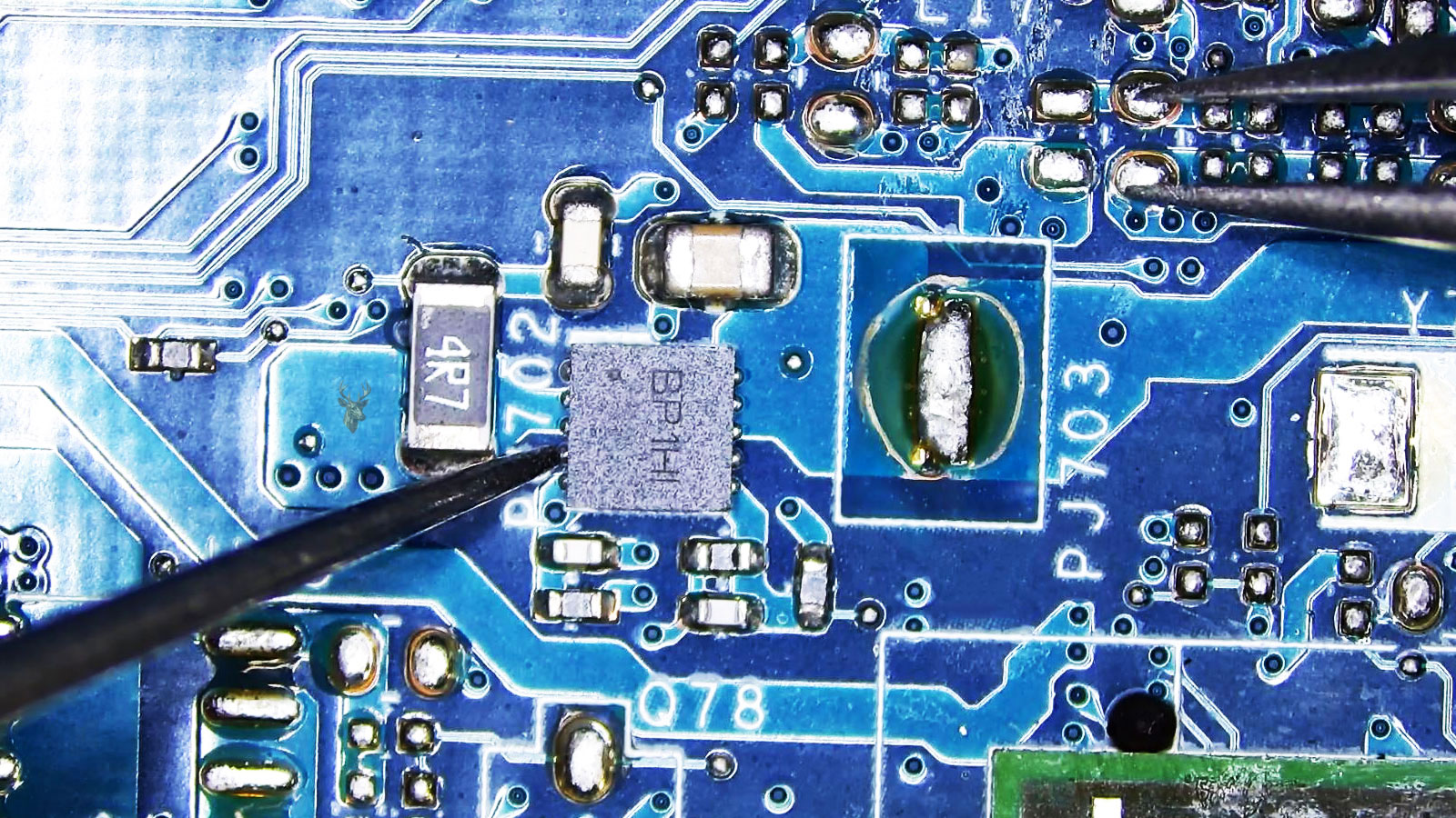 Close-up of a circuit board with a BP1H1 IC chip being tested with a multimeter while tweezers touch two solder pads.