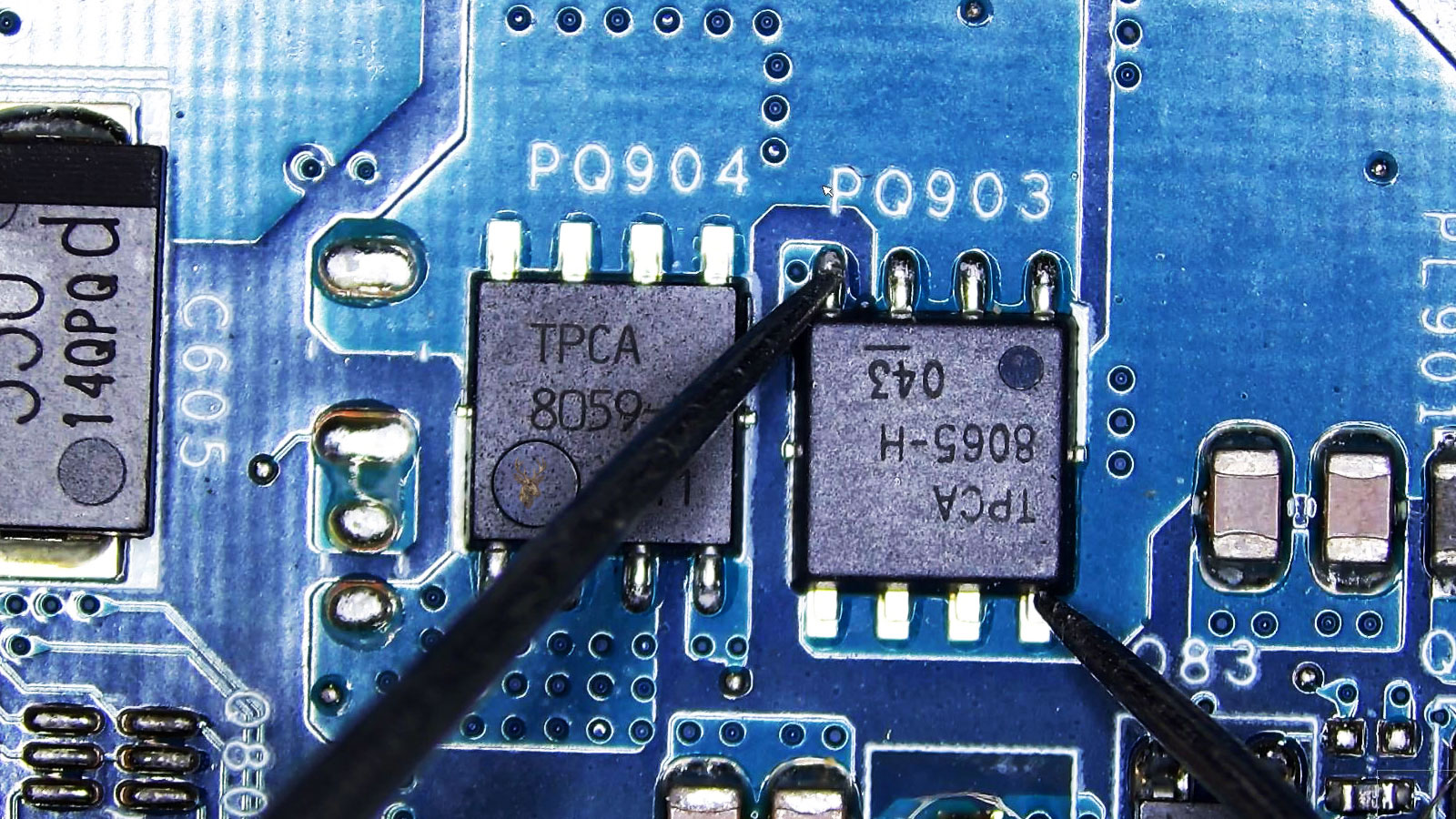 Close-up of a computer circuit board with MOSFET PQ903 being tested from gate to drain near PQ904 and surrounding components.