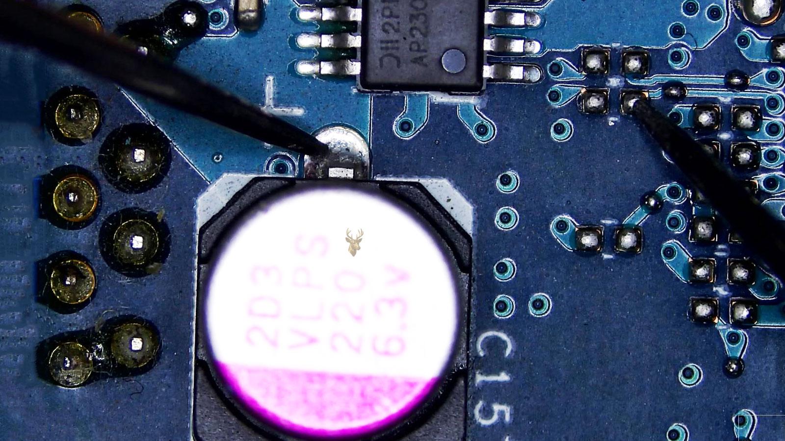 Multimeter probes checking for shorts between a capacitor and an integrated circuit on a computer circuit board.