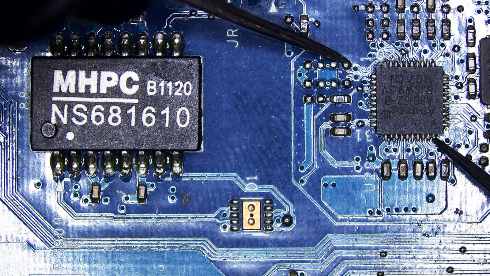 Multimeter probes testing pins on a 40-pin controller IC on a computer circuit board.