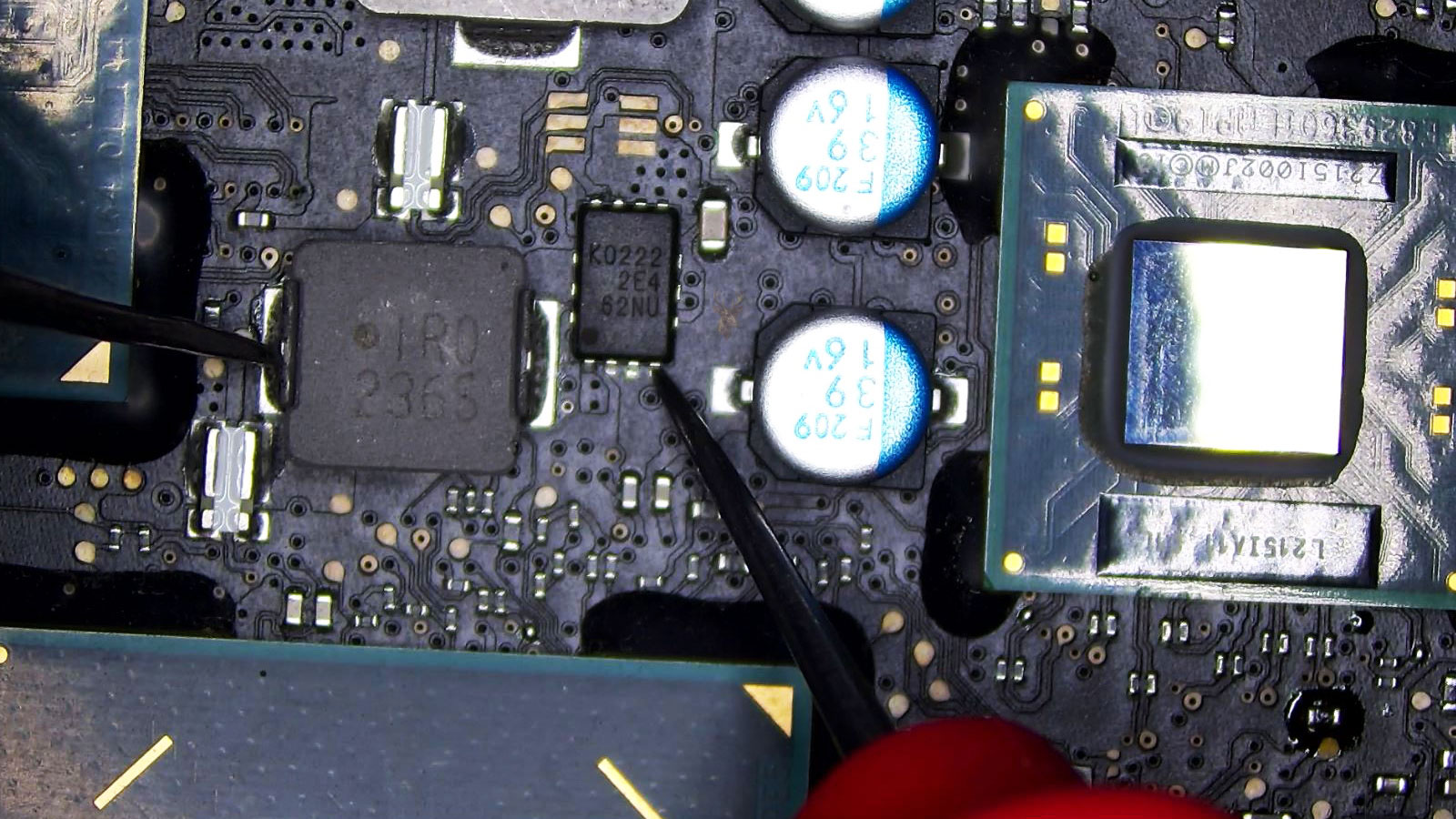 Multimeter leads checking an IC chip for shorts on a computer circuit board.
