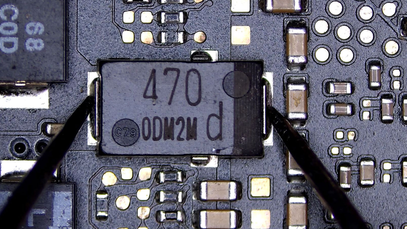 Close-up of a computer circuit board featuring a five-pin IC chip surrounded by capacitors, resistors, transistors, and other electronic components.