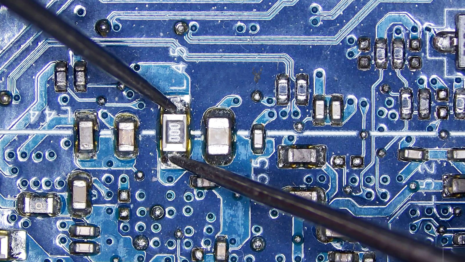 Multimeter probes testing a 000 fuse on a computer circuit board.