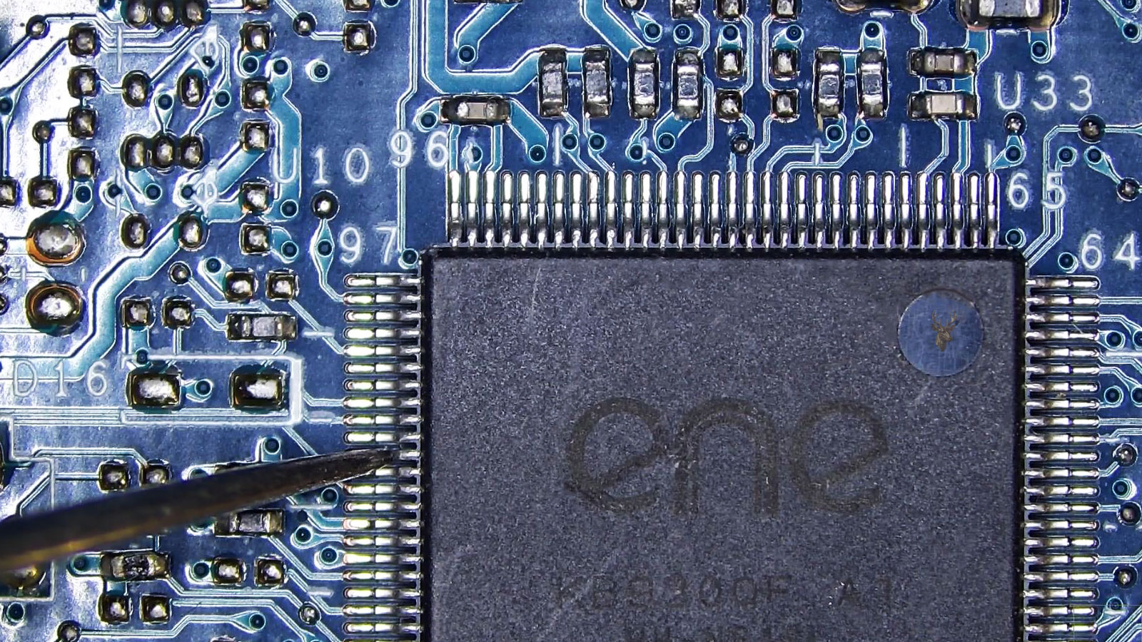 Probe touching a pin of the ENE Super I/O chip labeled U33 on a computer circuit board with surrounding electronic components.