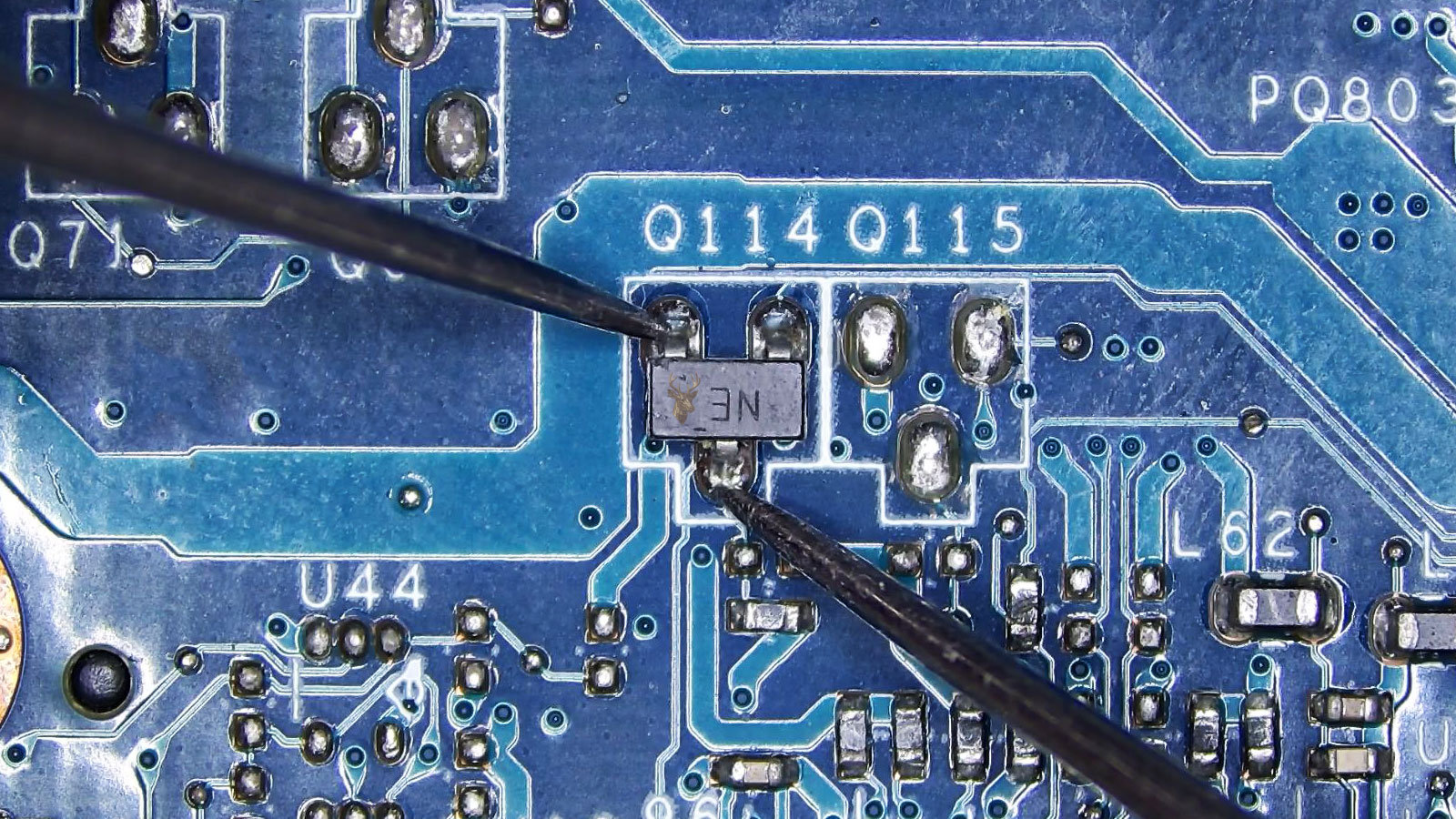 Multimeter probes testing a three-leg transistor marked "NE" on a computer circuit board with surrounding electronic components.