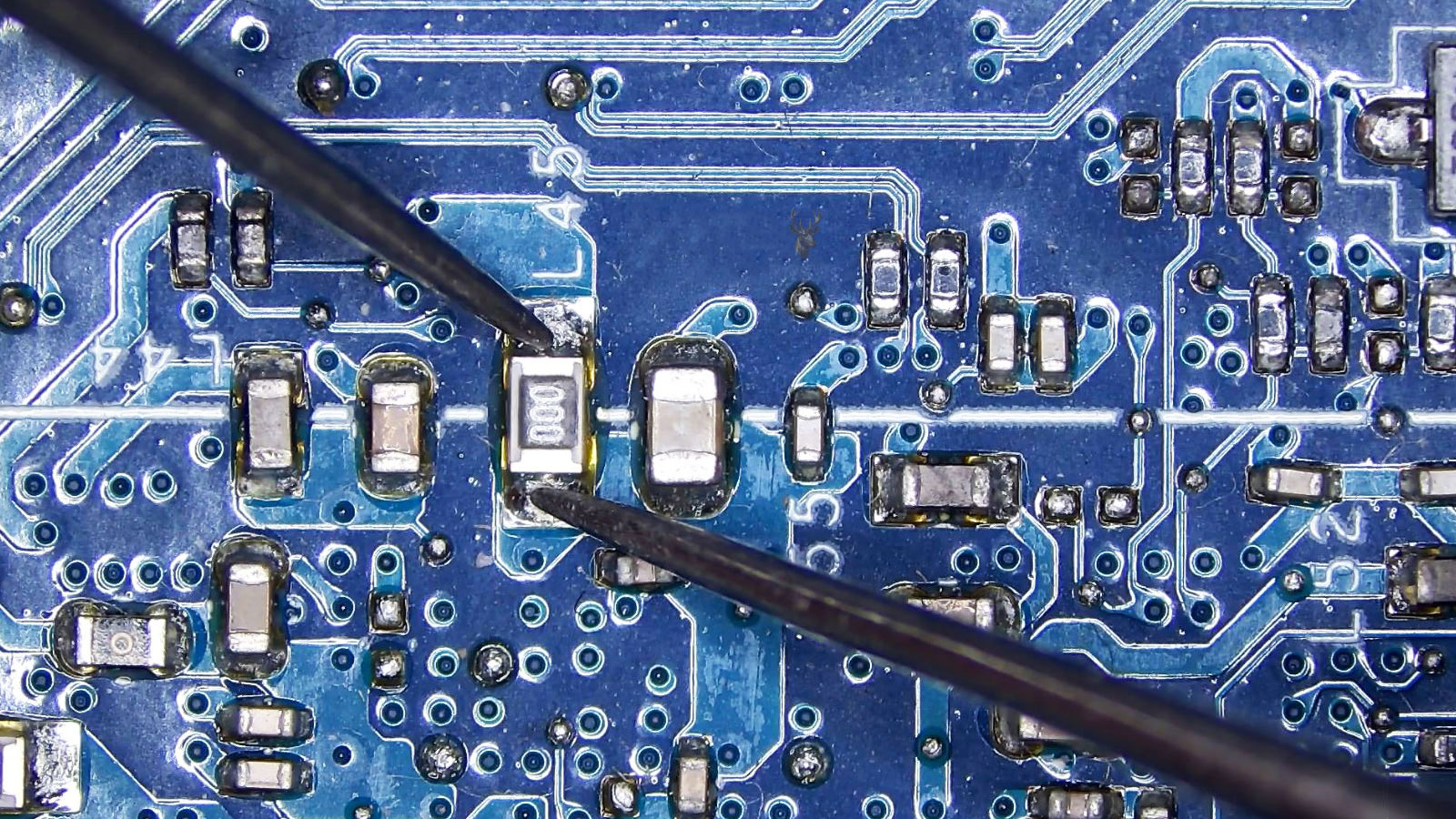 Multimeter probes testing a 000 fuse on a computer circuit board.