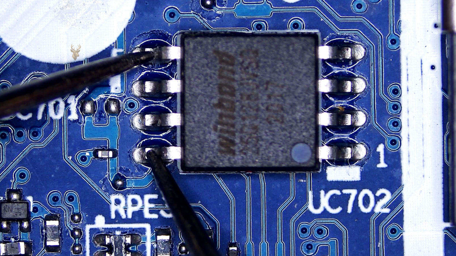 Multimeter probes measuring pins 5 and 8 of a Winbond BIOS chip on a computer circuit board.