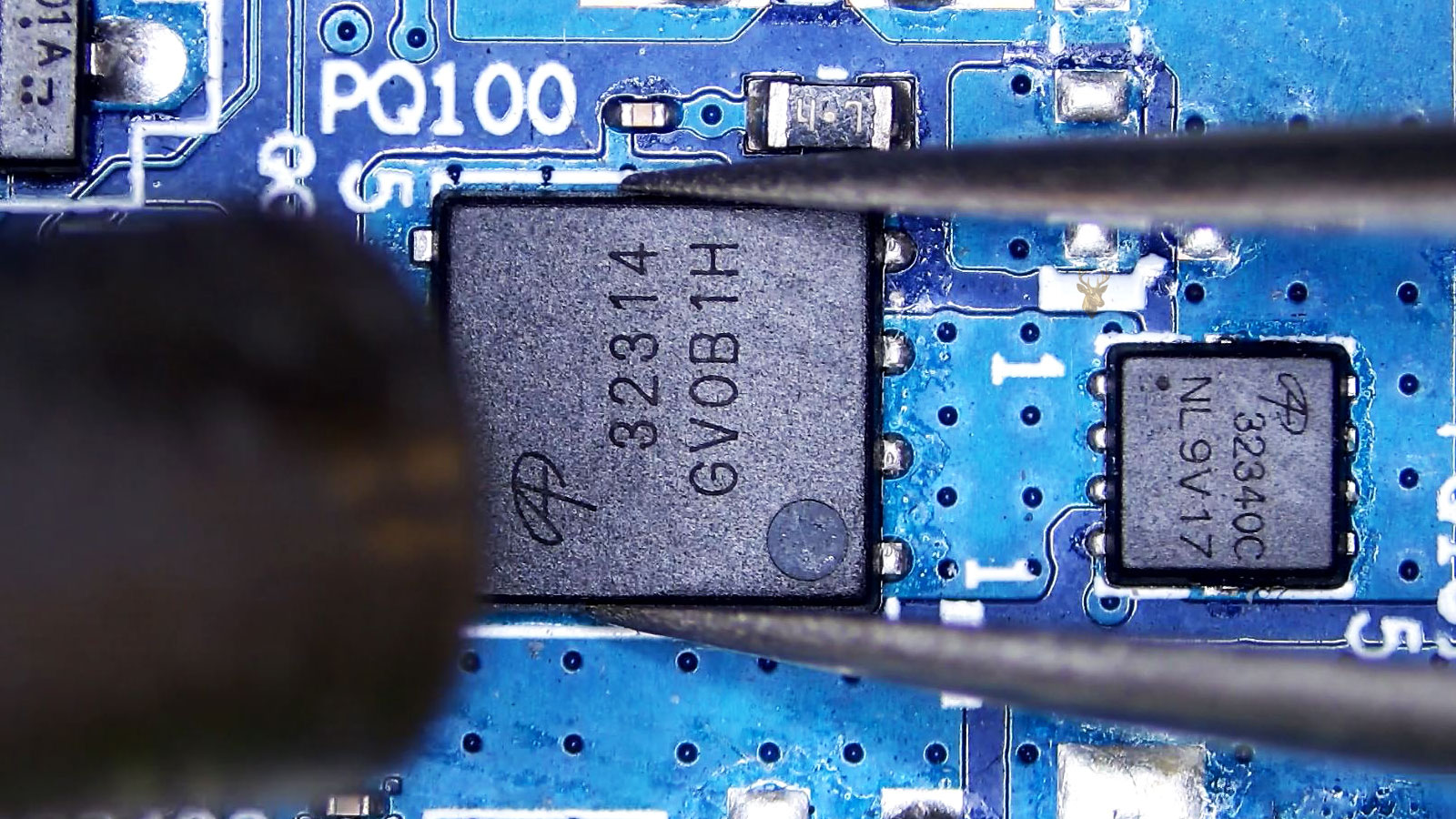 Tweezers holding the center A32314 MOSFET while a hot air gun nozzle points toward it.