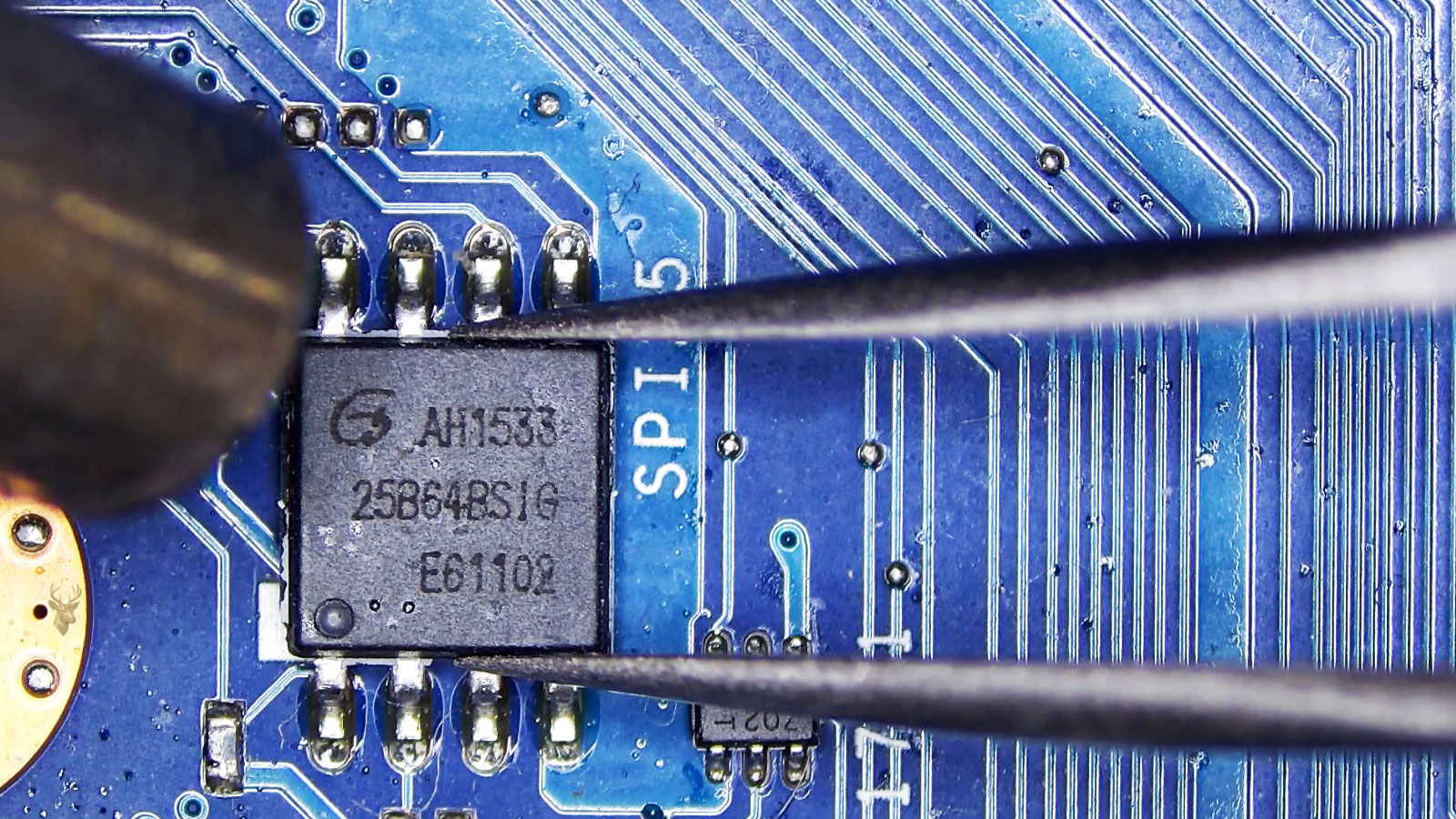 Tweezers holding the AH1533 MOSFET while a hot air station points at it beside a small power IC.