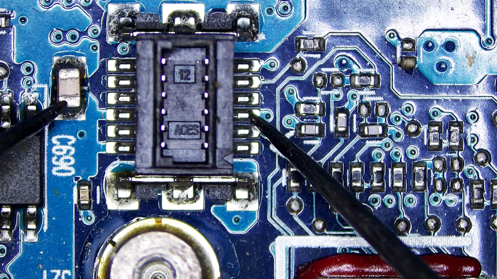 Multimeter probes measuring from one end of capacitor C690 to a pin on the opposite side of the 12-pin connector.
