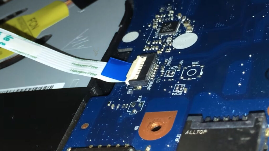 Laptop flex cable with small tears and a potentially broken conductive line.