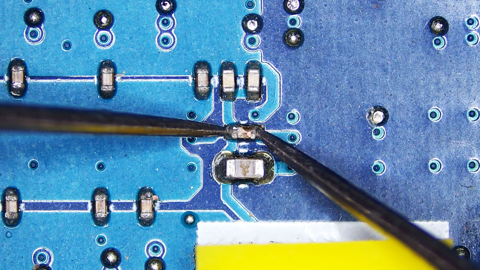 Damaged SMD capacitor being measured among several small capacitors on a computer circuit board.