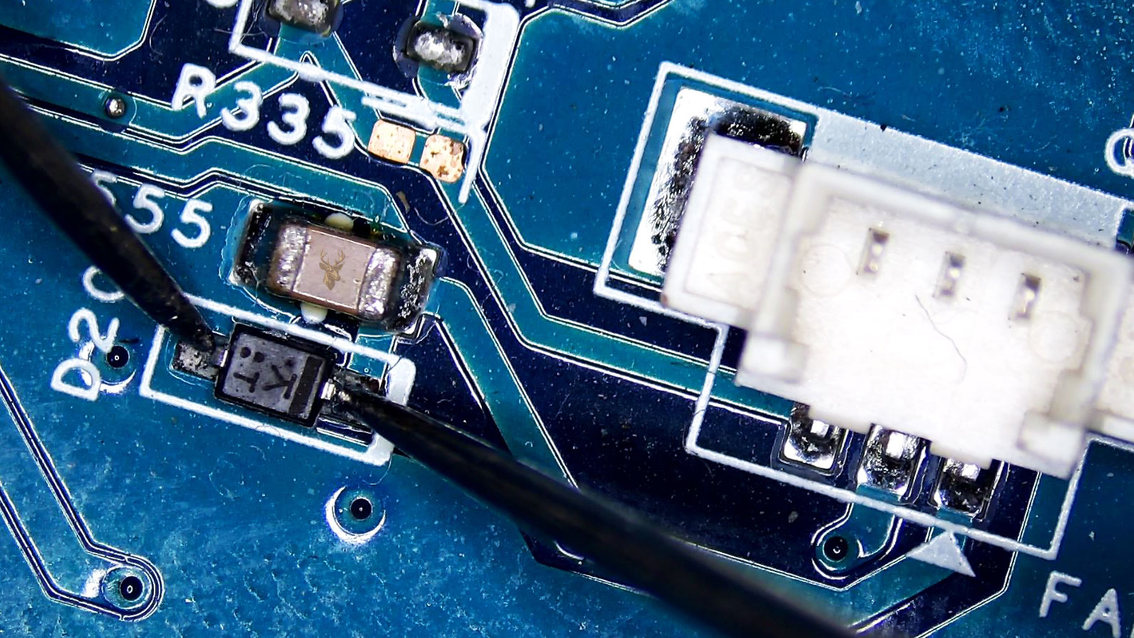 Diode being measured next to a three-pin plastic connector with a nearby capacitor.