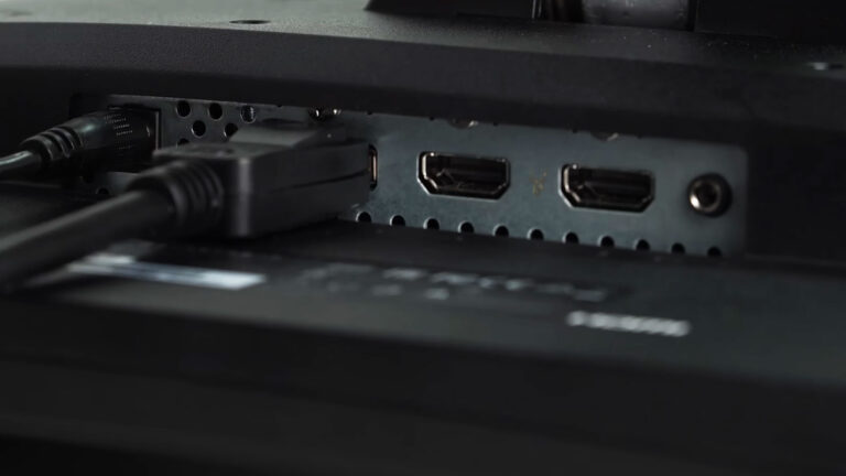 Rear panel of a computer monitor with a DisplayPort cable connected beside multiple HDMI ports.