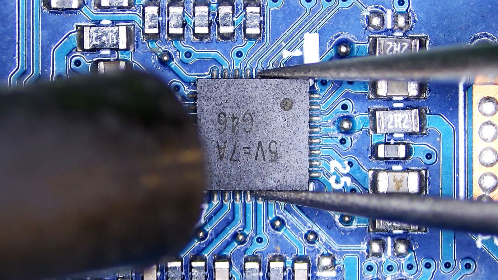 G46 5V 7A power regulator IC held by tweezers while a hot air station points at it.