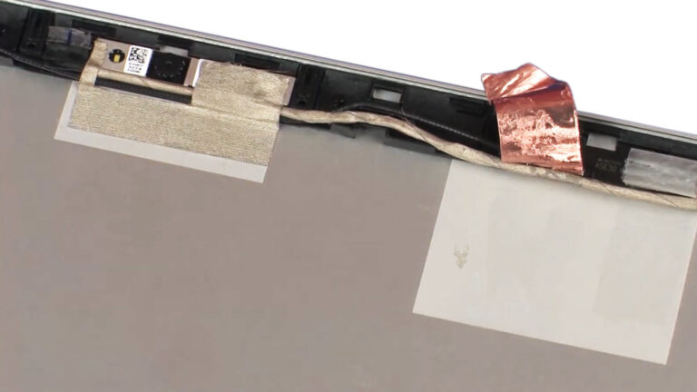 Laptop display cable routed through the rear display housing and hinge area before connecting to the LCD panel.
