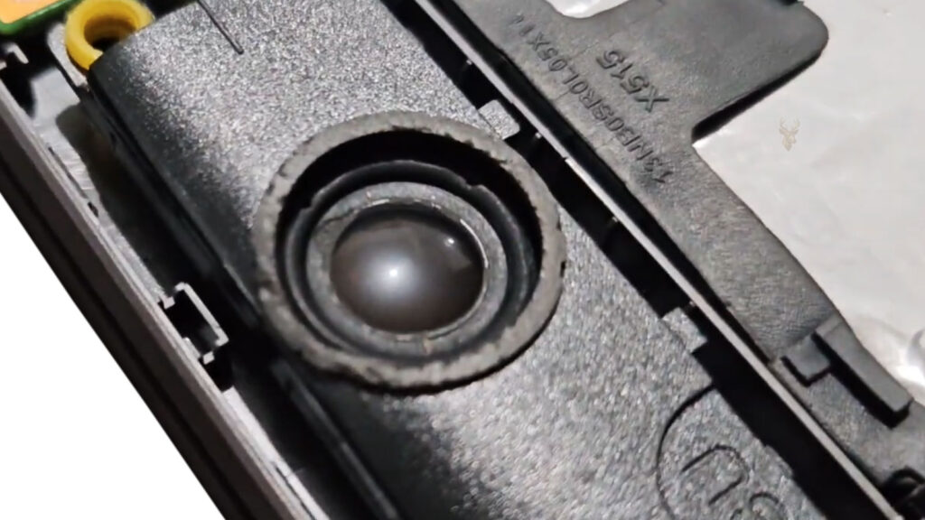 Damaged laptop speaker with a cracked and loosened center, representing audio that crackles, distorts, or stops working at certain volumes.