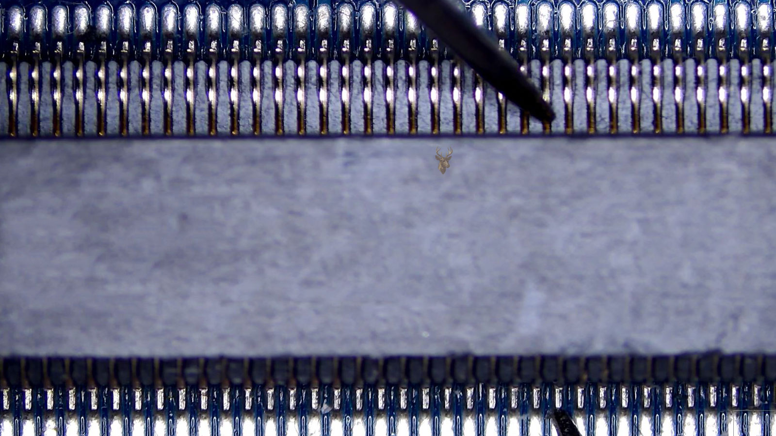 Measurement probes touching matching pins on opposite sides of a memory slot socket on a computer circuit board.