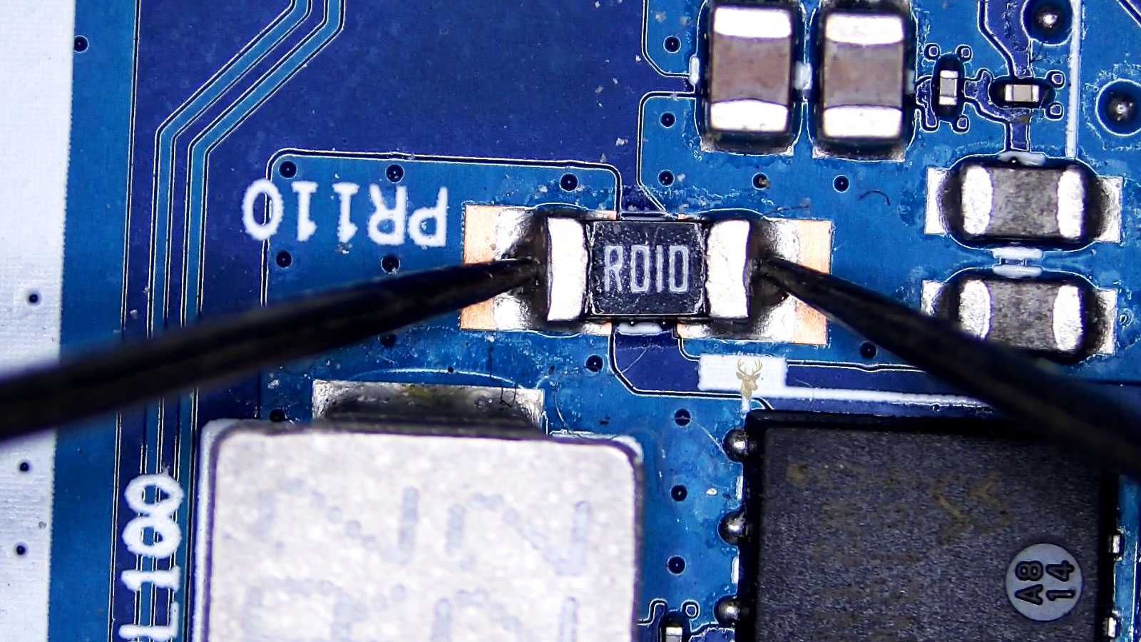 PR110 R010 resistor being measured near a coil, MOSFET, SMD capacitors, and resistors.