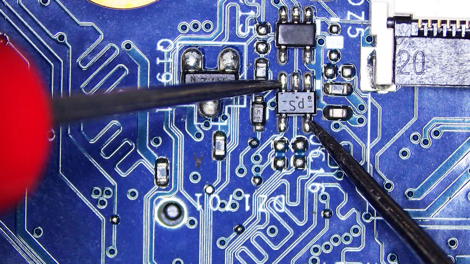 Power controller being measured at several legs beside a transistor, capacitor, resistors, and diodes on a computer circuit board.