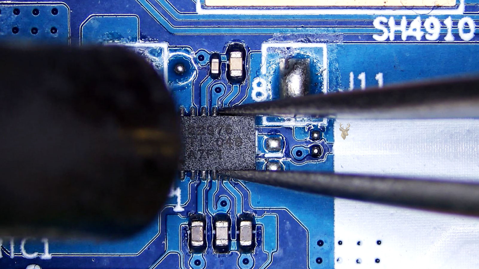 Tweezers holding the U13 22976 IC while a hot air station nozzle points toward it.