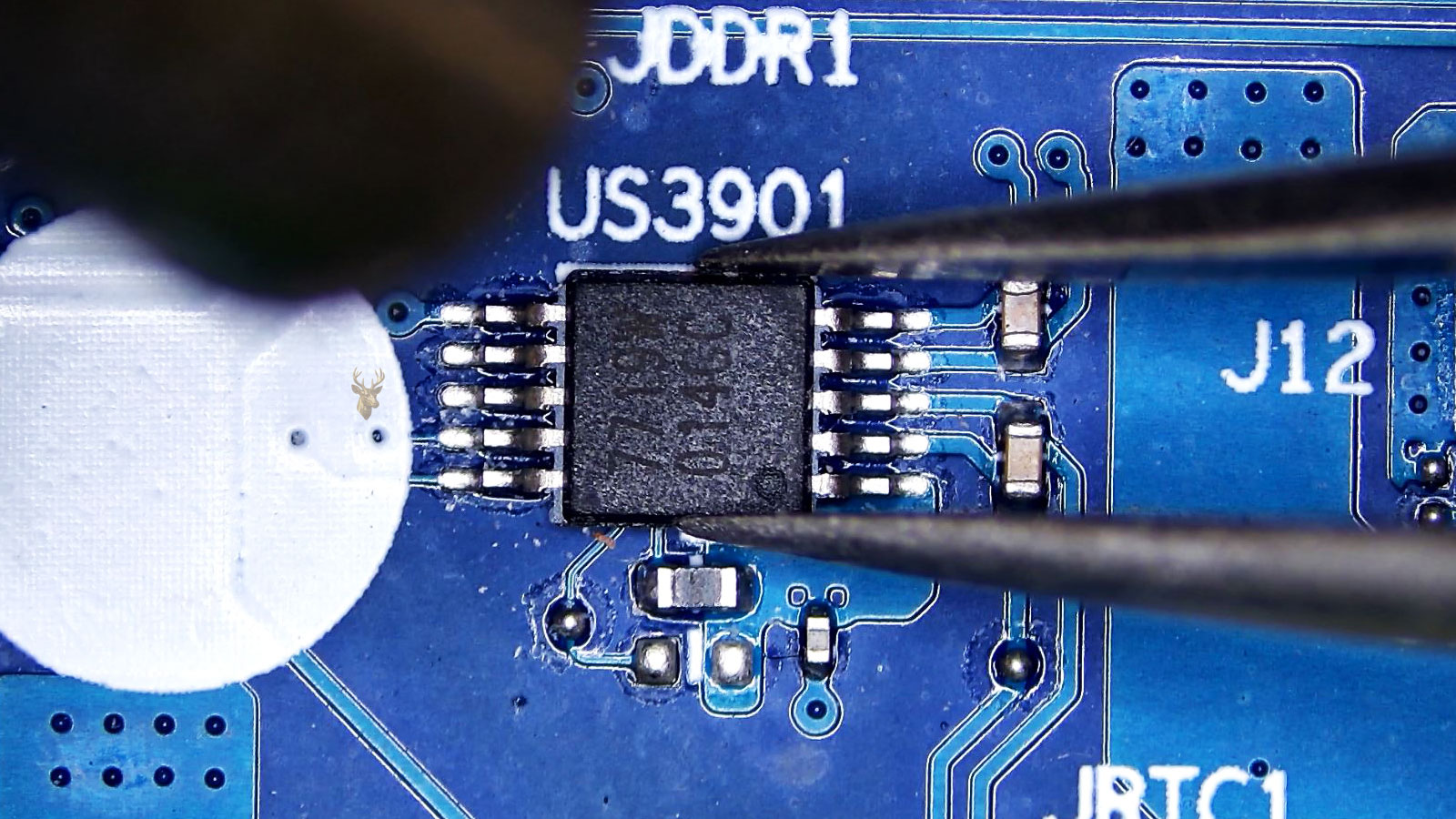 US3901 10-leg IC held by tweezers while a hot air station nozzle points at it near capacitors and resistors.