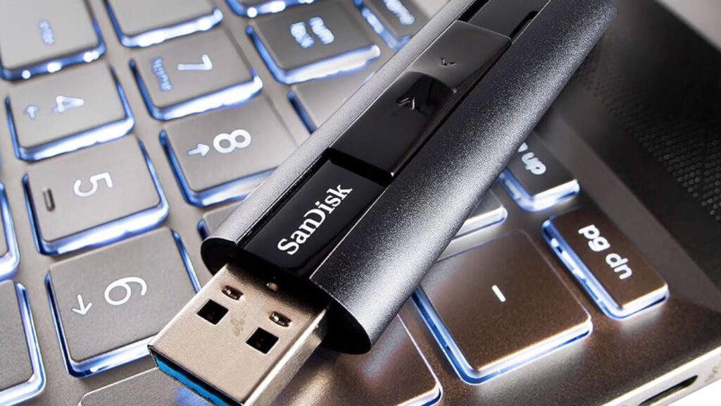 SanDisk USB flash drive resting on a laptop keyboard, representing a USB device that works in BIOS but stops responding after Windows starts.