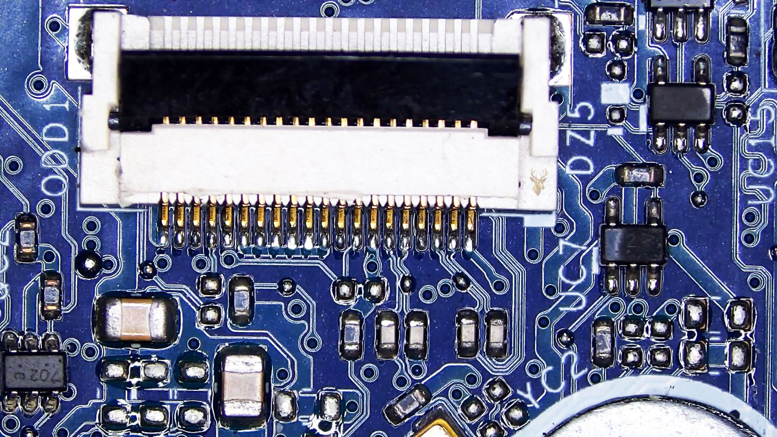 White plastic multi-pin connector surrounded by capacitors, transistors, ICs, power transistors, and power IC chips.