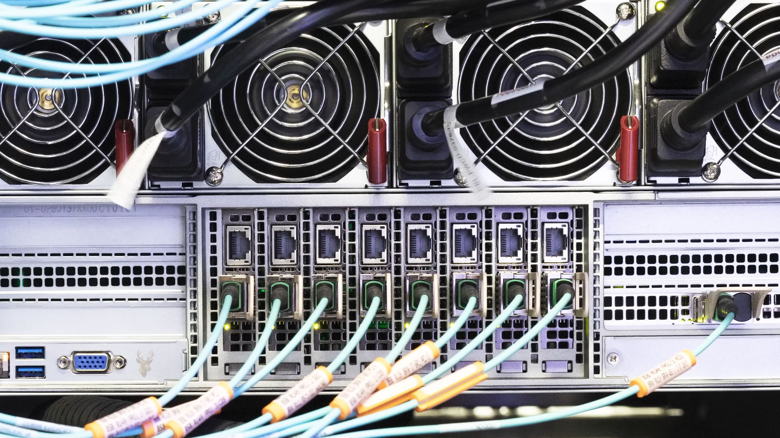 Rear view of business network equipment with power supplies, cooling fans, and connected network cables.