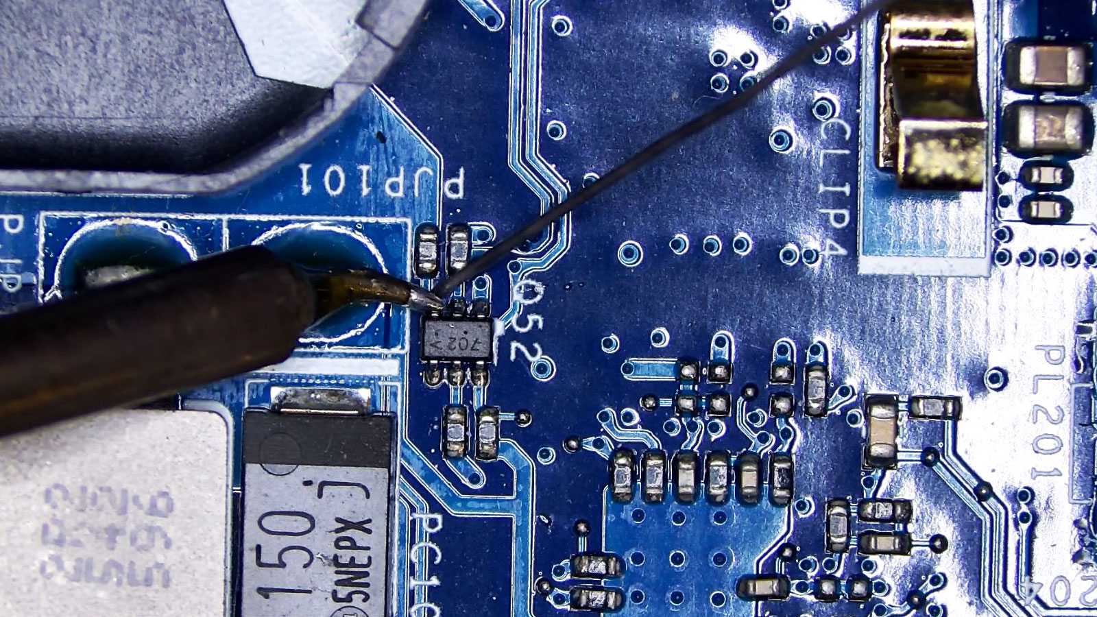 IC702 chip with six pins being repaired using precision microsoldering.