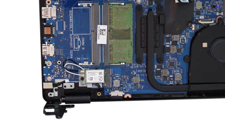 Laptop with the display hinge lifted to expose the DC charging jack during inspection of a charging port problem.