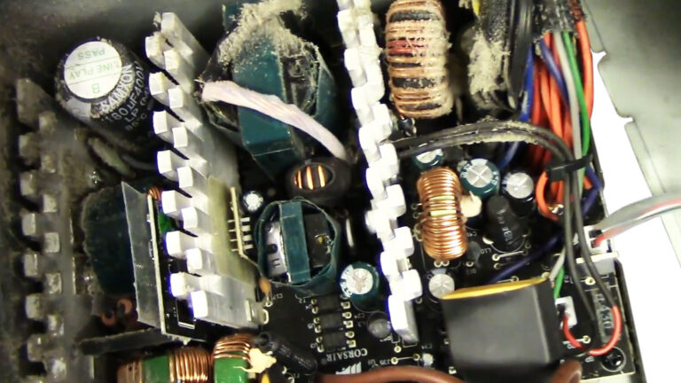 Open desktop power supply with heavy dust buildup and aging internal components during diagnosis of repeated computer crashes.