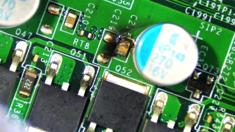 Lenovo ThinkCentre motherboard with a burned and exploded C215 ceramic capacitor causing a no-display condition.
