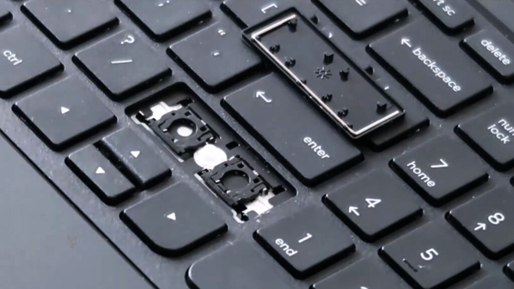 Laptop keyboard with the right Shift key removed, exposing the key mechanism underneath during troubleshooting.