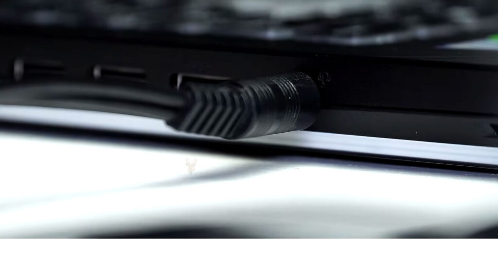 Side of a laptop showing an audio cable connected to the headphone and microphone port during sound troubleshooting.