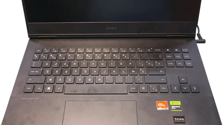 Powered-on Omen laptop with illuminated power and Caps Lock LEDs while the display remains black after the lid is opened.