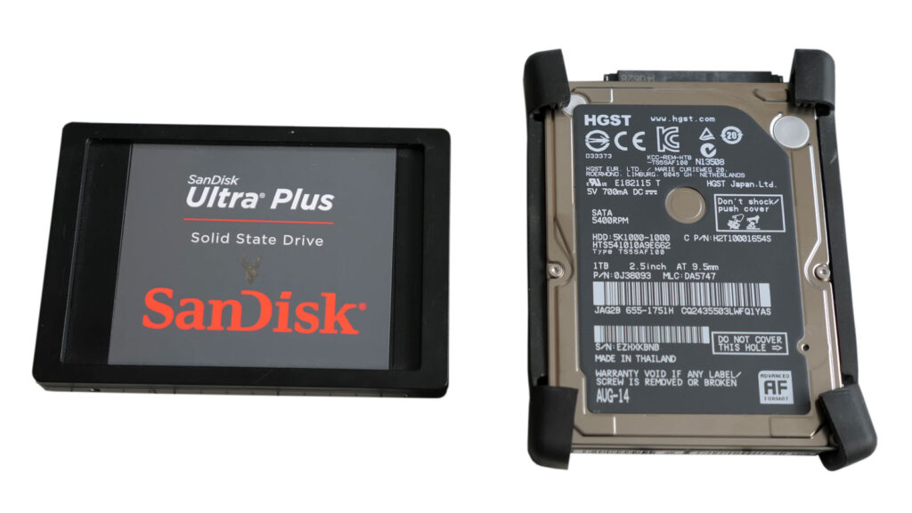SanDisk Ultra Plus solid-state drive beside an HGST 2.5-inch hard drive during an iMac storage upgrade.