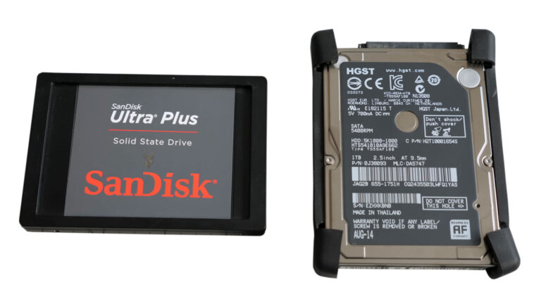 SanDisk Ultra Plus solid-state drive beside an HGST 2.5-inch hard drive during an iMac storage upgrade.