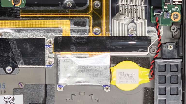 Yellow CMOS battery with red and black wires connected to the motherboard to maintain the system clock and BIOS settings.